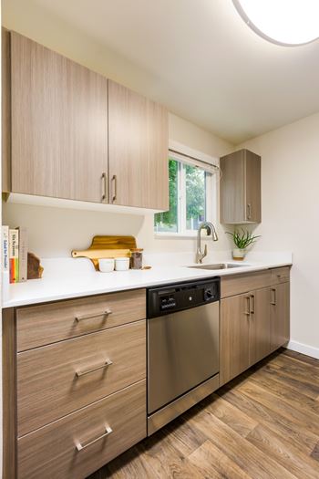 A kitchen with wooden cabinets and a stainless steel dishwasher.